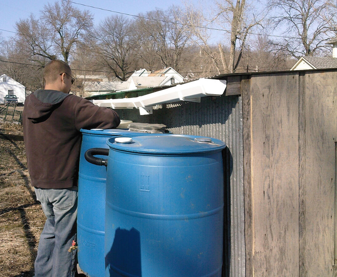 Chris Alliman installs our rain barrels with gutter help from Mitch Kaufman (not pictured but always in the background!) Chris Alliman installs our rain barrels with gutter help from Mitch Kaufman (not pictured but always in the background!)